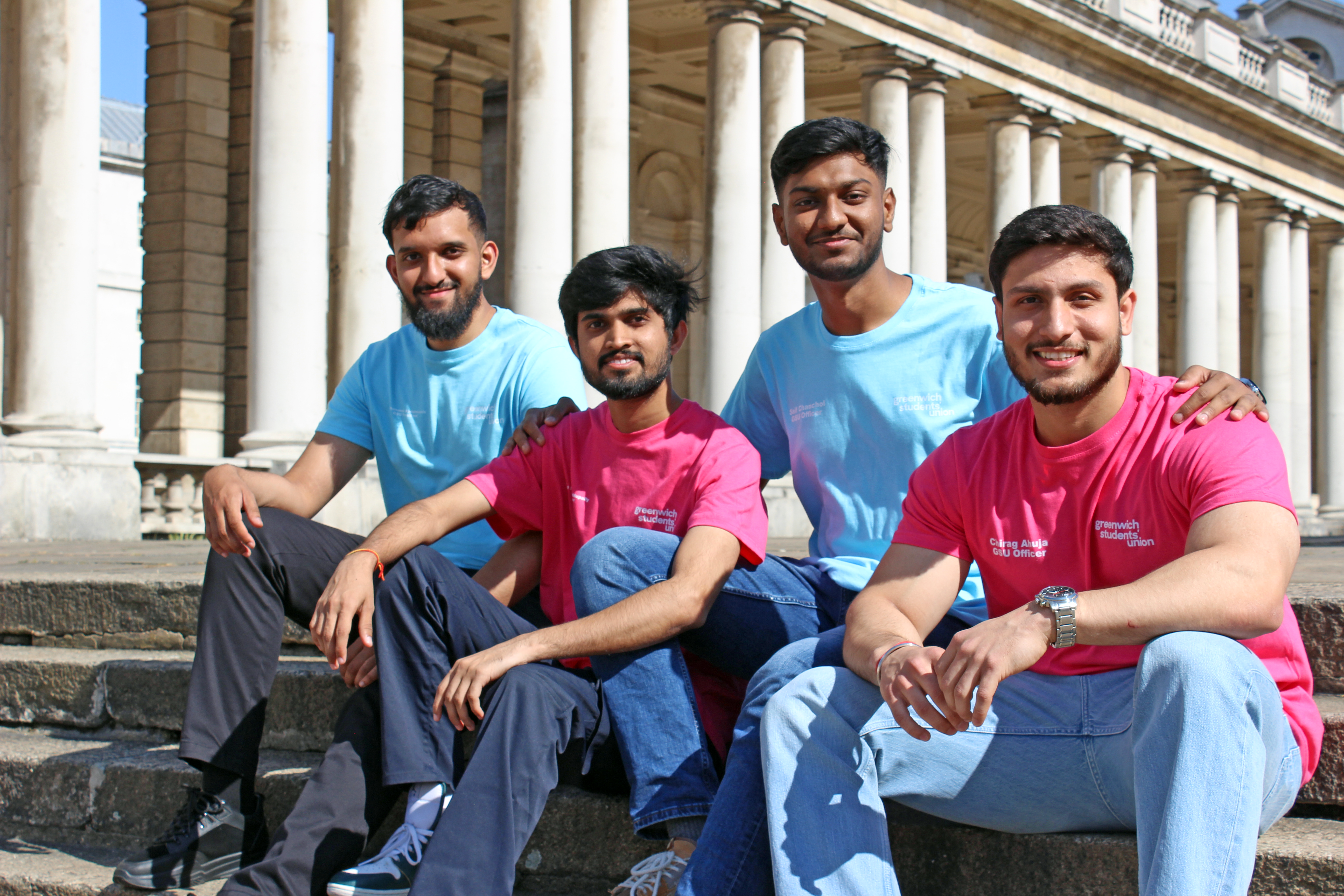 the 4 officers sat on the steps by Queen Anne building at the university of greenwich wearing alternating officer t shirts in pink and blue