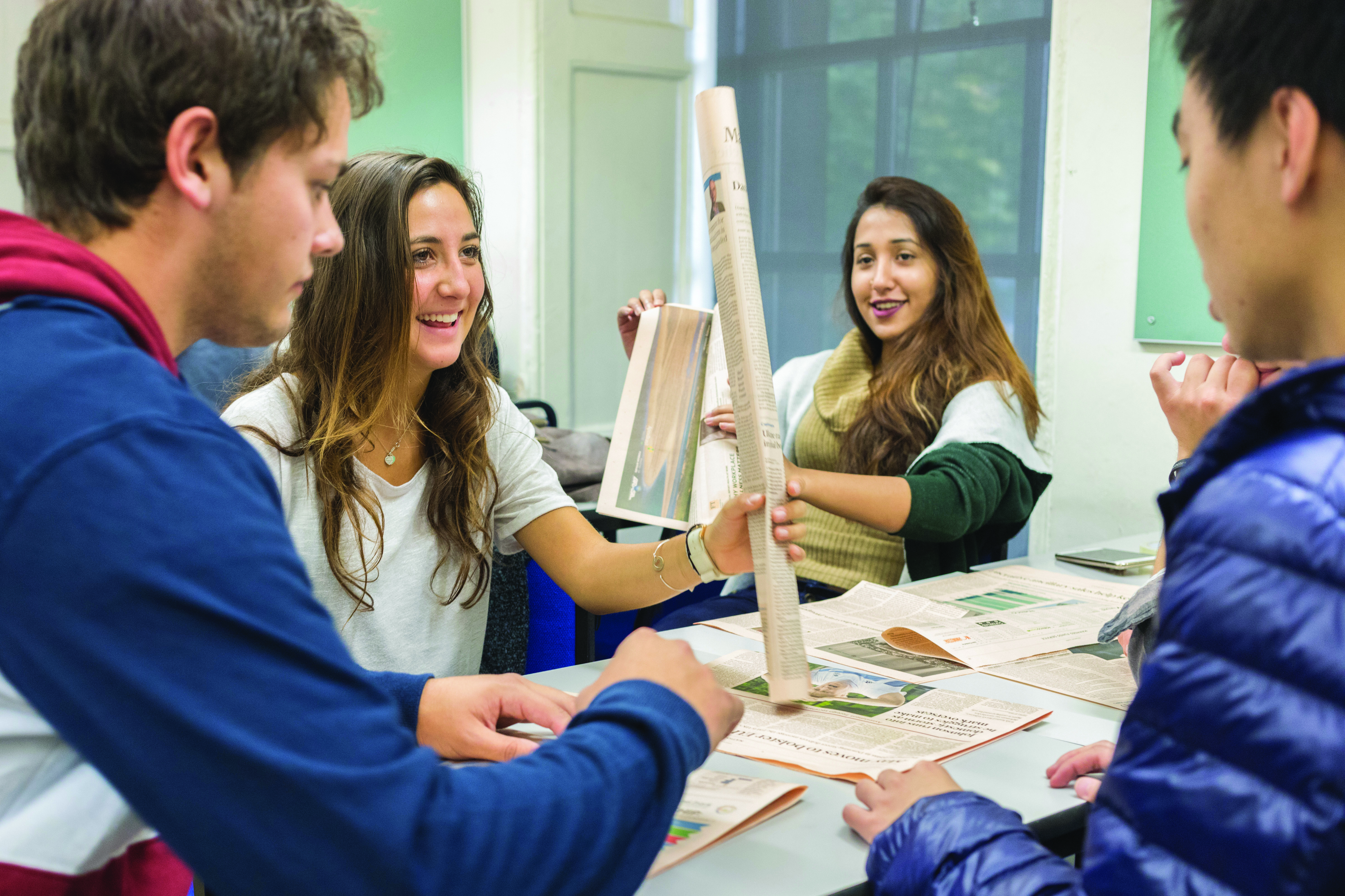 group of students around a table smiling and working on a team building project together