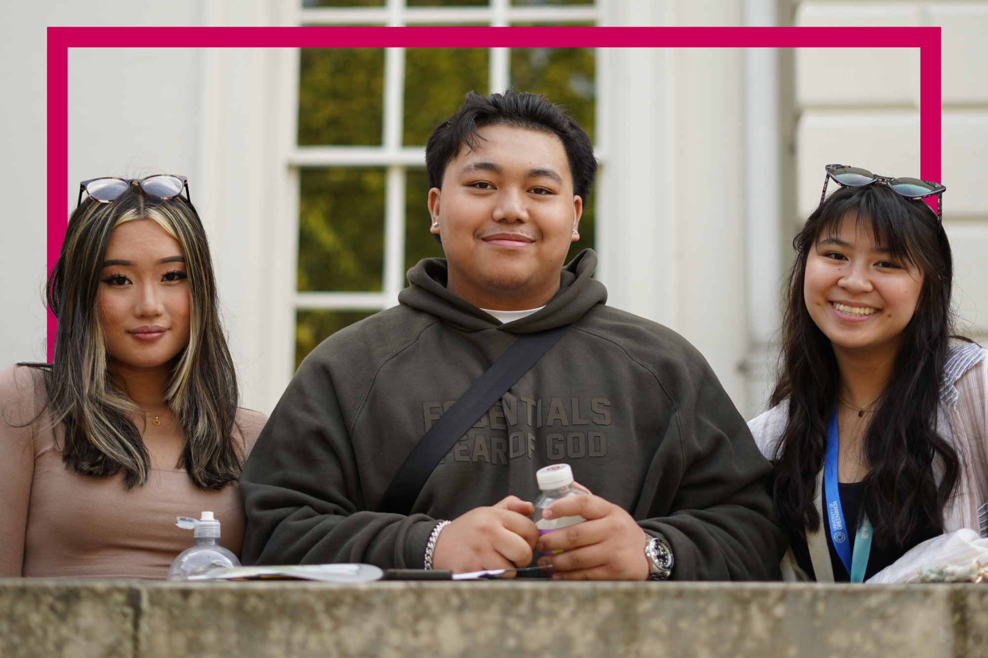 three students leaning on wall smiling to the camera