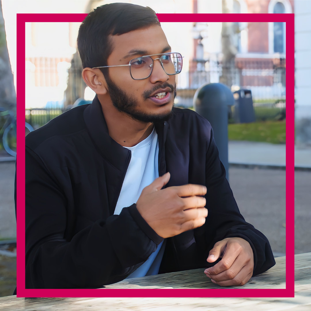 student outside at picnic table wearing glasses and in mid conversation