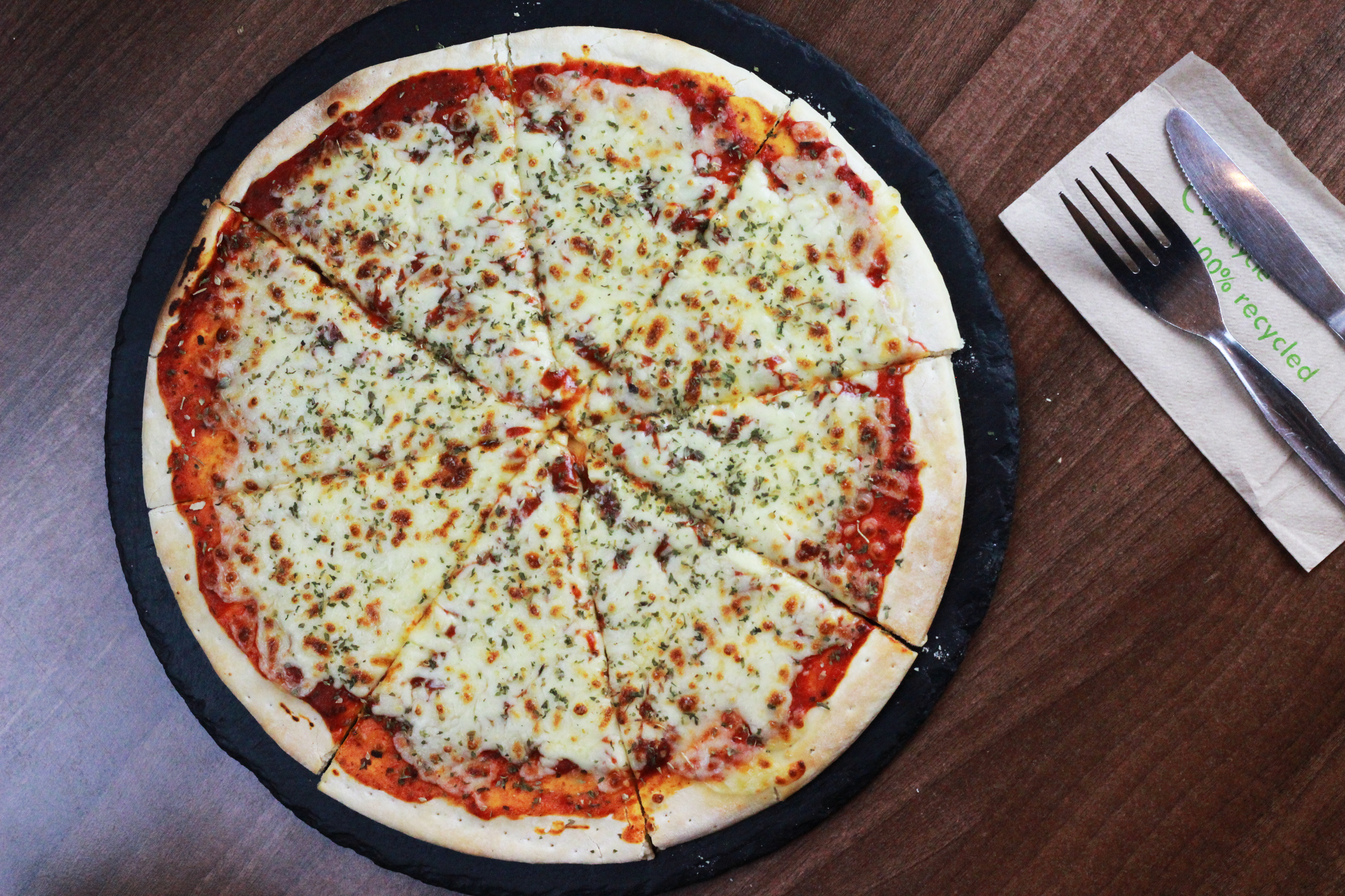 pizza on table with cutlery laid out to the side