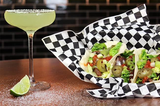 three tacos in a basket, alongside a Margarita cocktail in a glass
