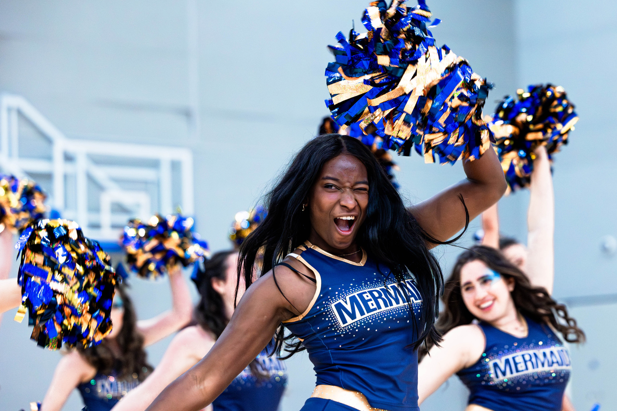 cheerleader smiling mid routine with pom poms