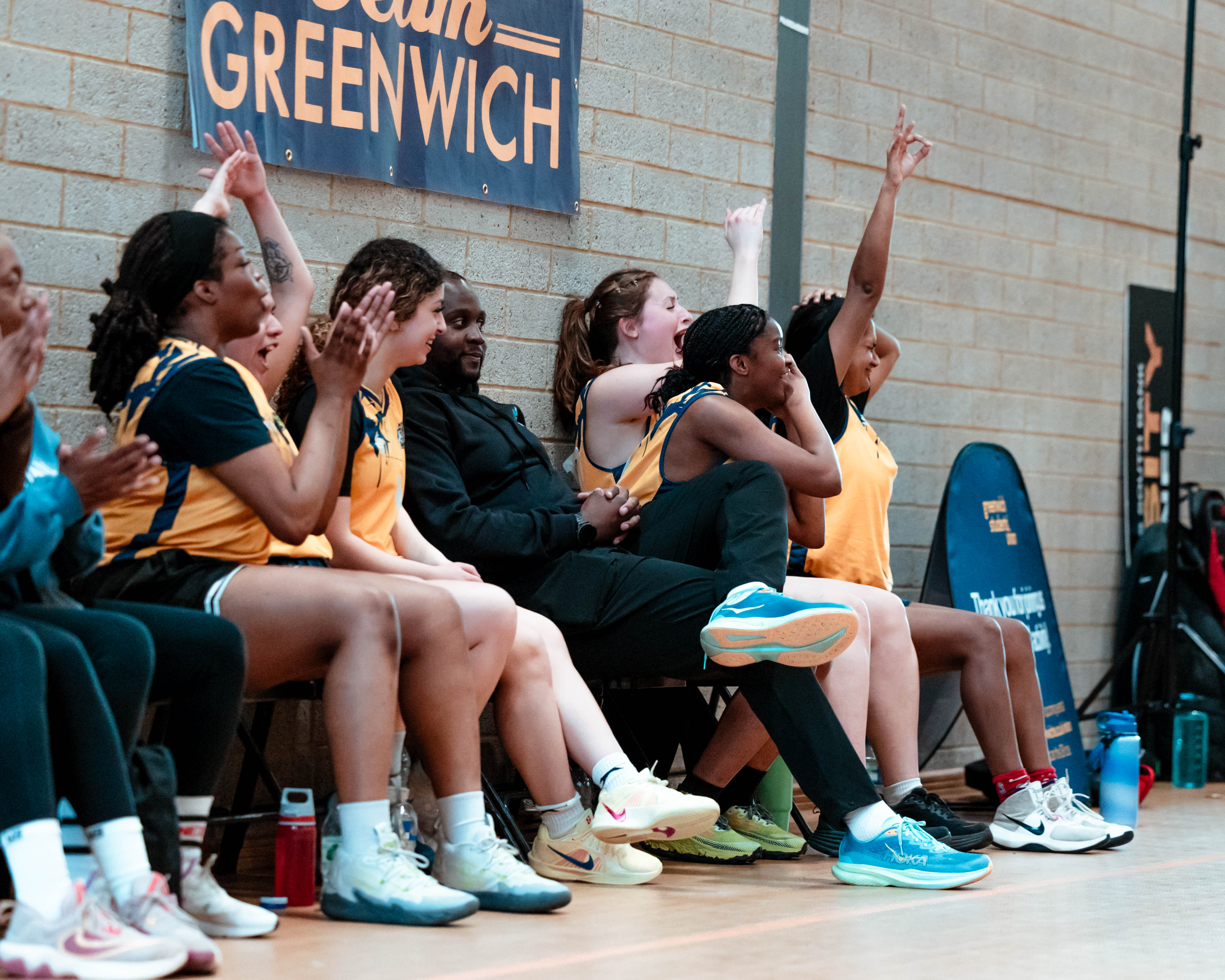 Womens basketball team sat on bench cheering on team mates