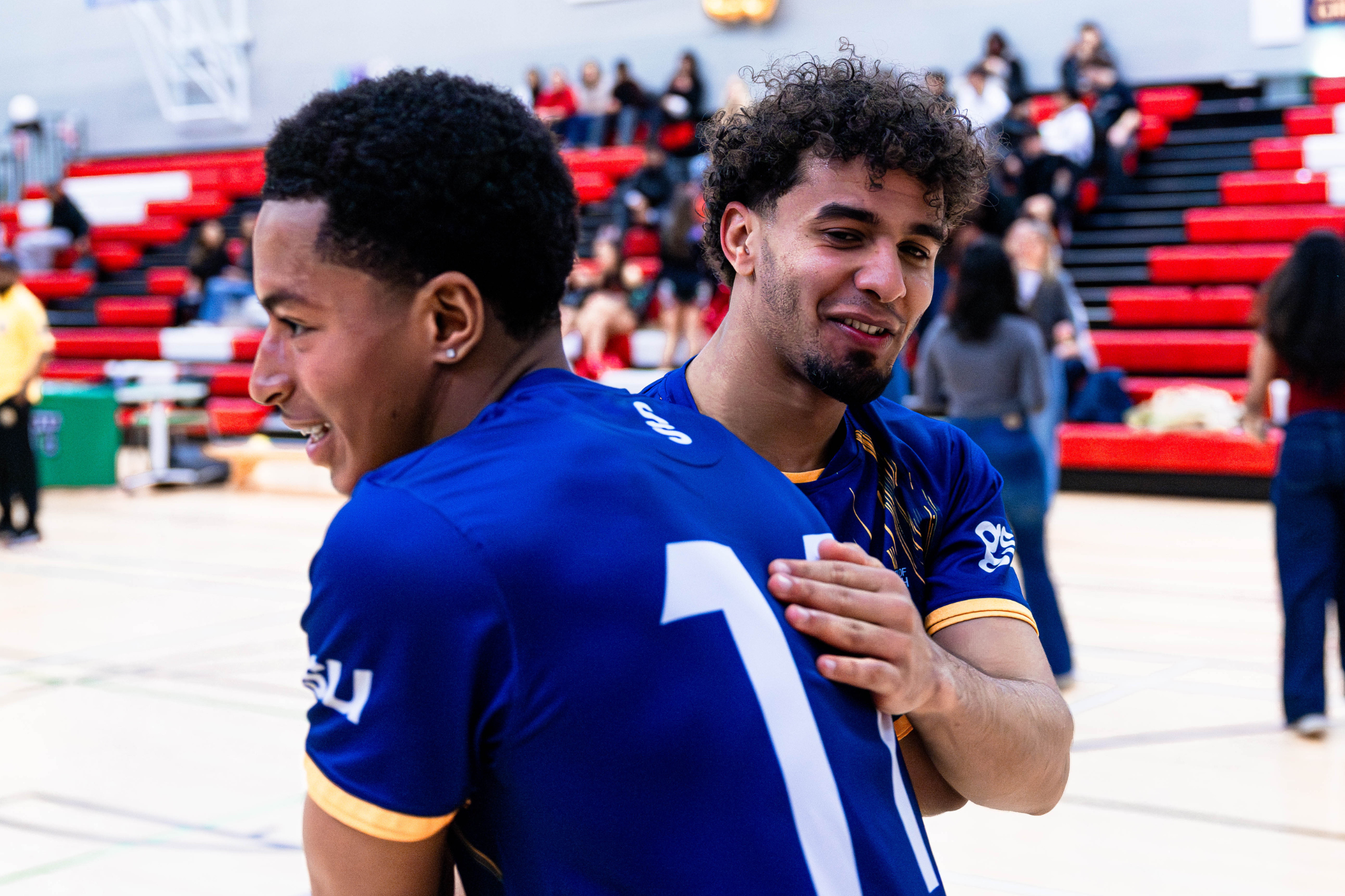 futsal players smiling, one with his back slightly to the camera the other mid hug