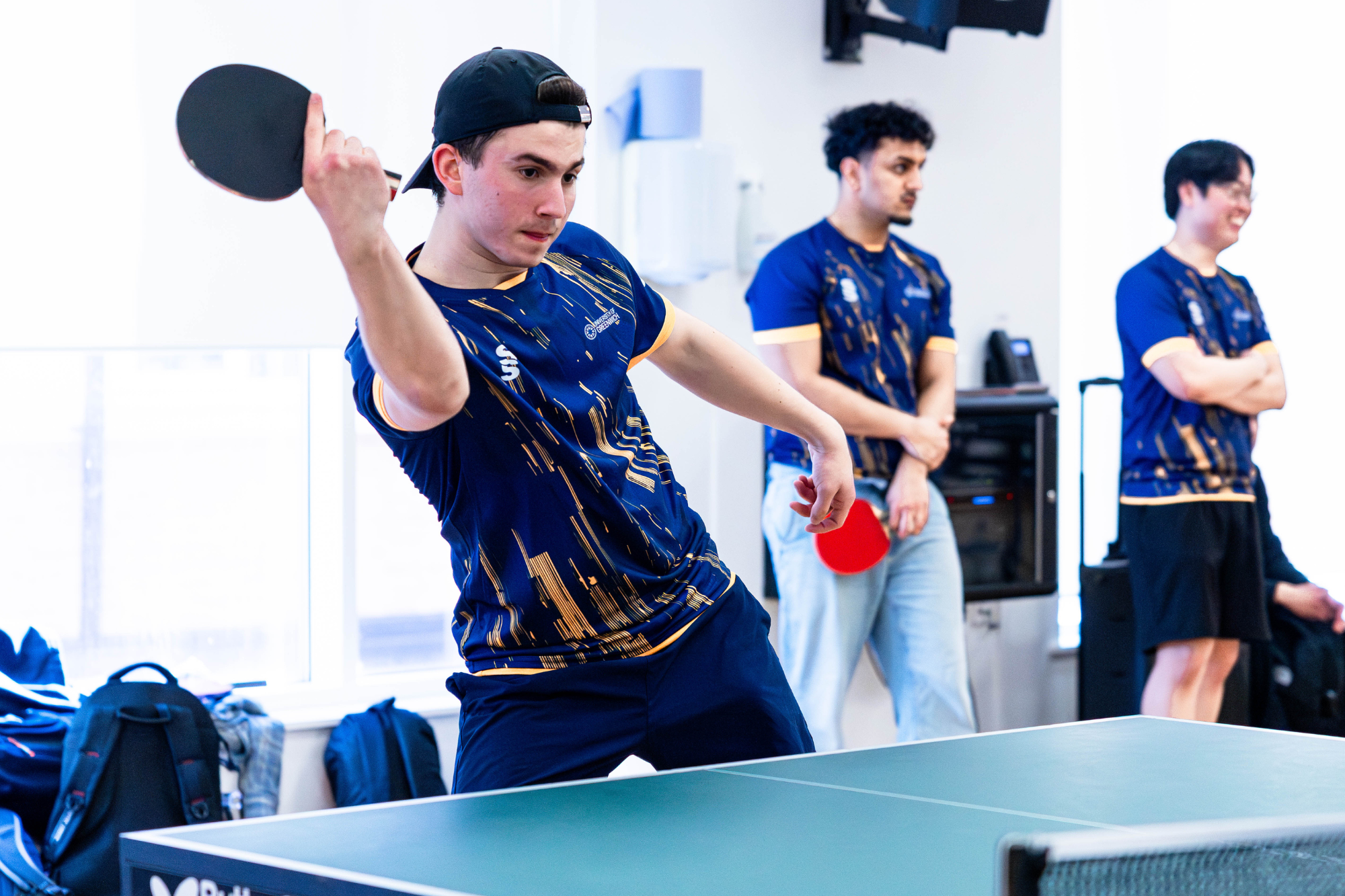 table tennis player mid game, wearing a cap