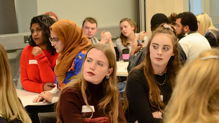 Students in a boardroom, all facing forward, looking at presentation off camera
